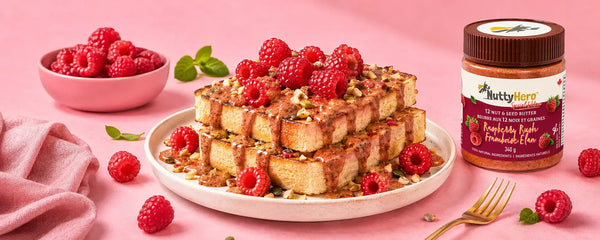 Stack of waffles with raspberries nut butter on a plate, accompanied by a jar of NuttyHero berry-flavored nut butter on a pink background.